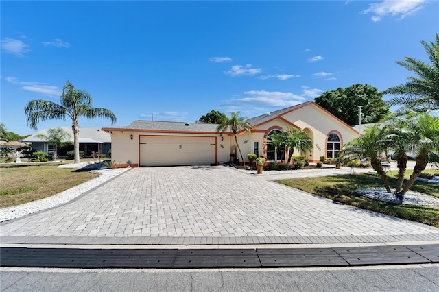 ranch-style house featuring decorative driveway, an attached garage, and stucco siding