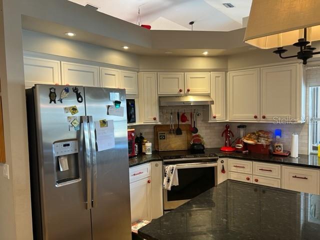 kitchen with decorative backsplash, under cabinet range hood, white cabinets, and appliances with stainless steel finishes