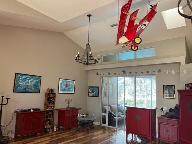 interior space featuring an inviting chandelier, wood finished floors, visible vents, and high vaulted ceiling