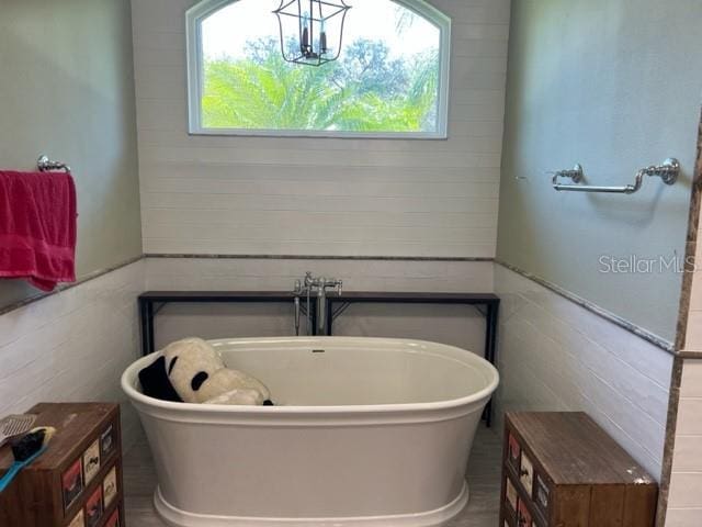 full bathroom featuring wainscoting, a freestanding bath, and tile walls