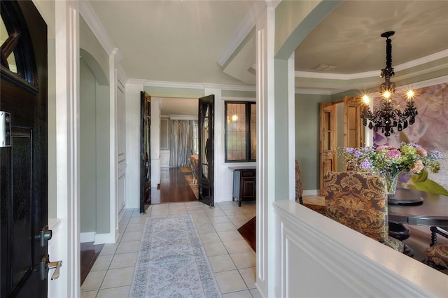 corridor featuring light tile patterned flooring, visible vents, crown molding, and an inviting chandelier