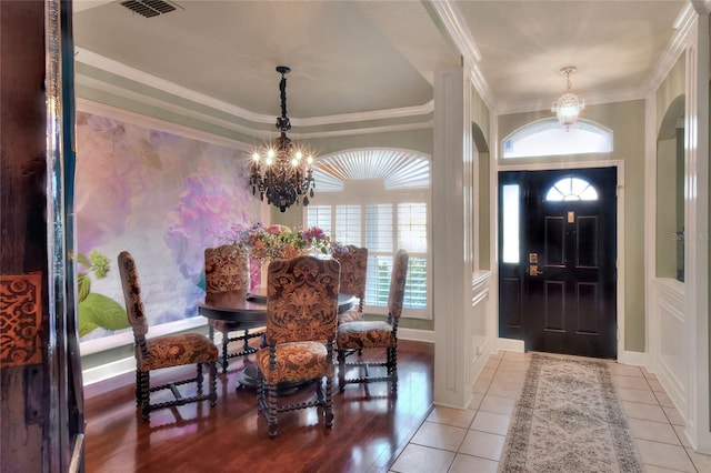 tiled entryway featuring visible vents, baseboards, ornamental molding, arched walkways, and a notable chandelier