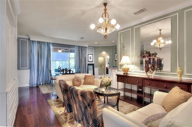 living room with a decorative wall, a notable chandelier, visible vents, and ornamental molding