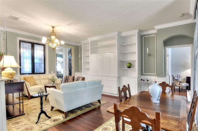 living area with a chandelier, visible vents, crown molding, and wood finished floors