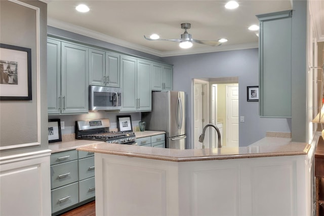 kitchen with stainless steel appliances, a peninsula, ceiling fan, and ornamental molding