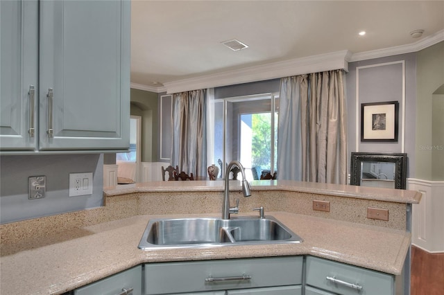 kitchen with visible vents, a sink, arched walkways, crown molding, and light countertops