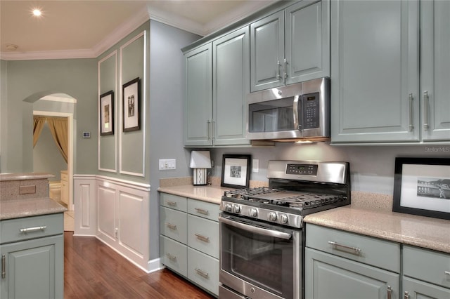 kitchen featuring stainless steel appliances, arched walkways, crown molding, light countertops, and dark wood-style flooring