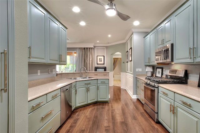 kitchen featuring a sink, stainless steel appliances, arched walkways, a peninsula, and crown molding