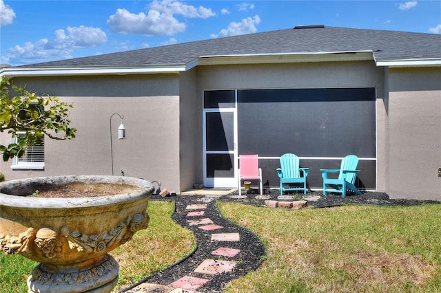 rear view of property with stucco siding, a yard, roof with shingles, and a sunroom