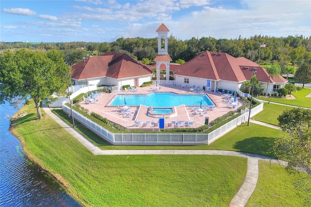 pool with a patio area, a lawn, a fenced backyard, and a water view