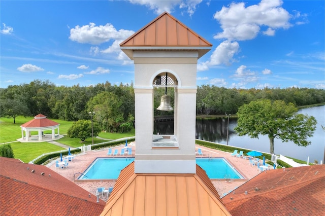 pool with a gazebo, a water view, a lawn, and a patio area