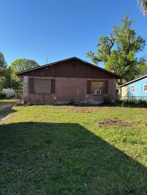 exterior space featuring brick siding, cooling unit, and a yard