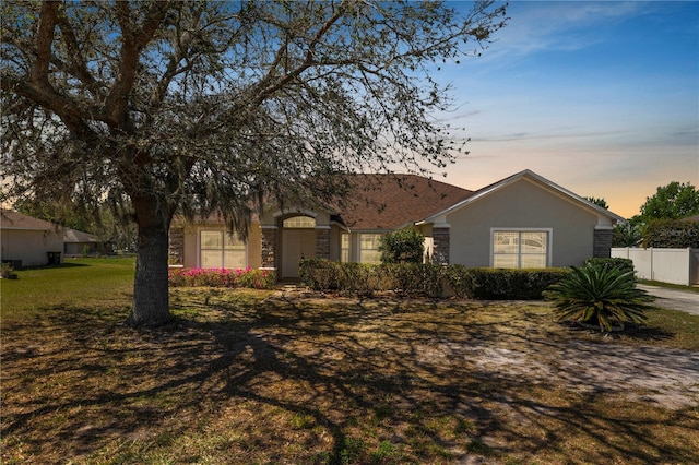 single story home with stucco siding, a front lawn, and fence