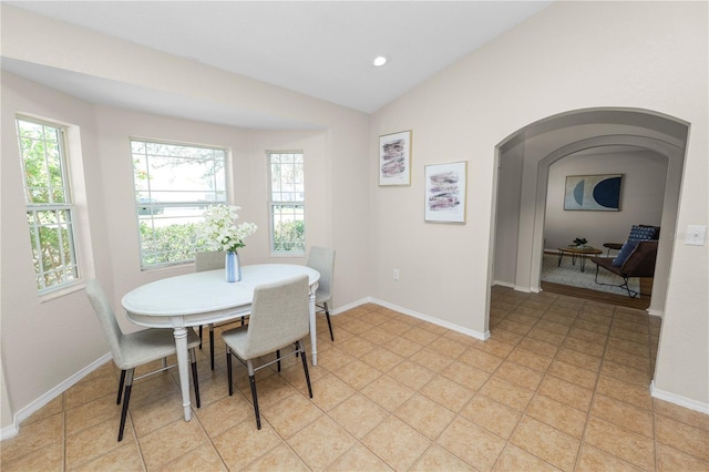 dining area featuring arched walkways, recessed lighting, baseboards, and lofted ceiling