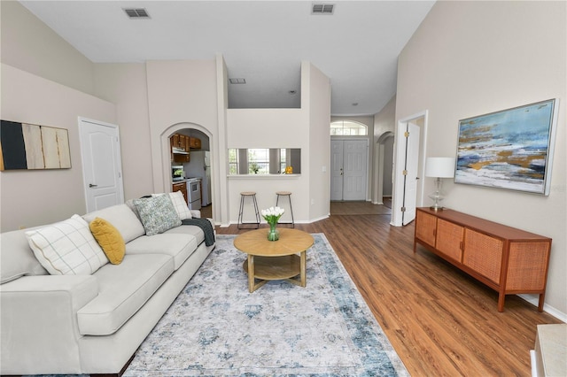 living area featuring visible vents, arched walkways, and wood finished floors