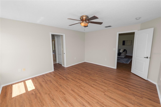 empty room featuring baseboards, a ceiling fan, visible vents, and light wood-type flooring