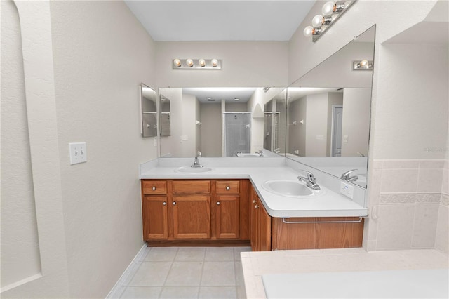 bathroom featuring a sink, double vanity, a shower stall, and tile patterned flooring