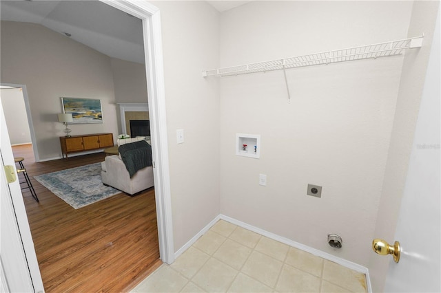 laundry area featuring laundry area, hookup for a washing machine, a tile fireplace, light wood-style floors, and hookup for an electric dryer