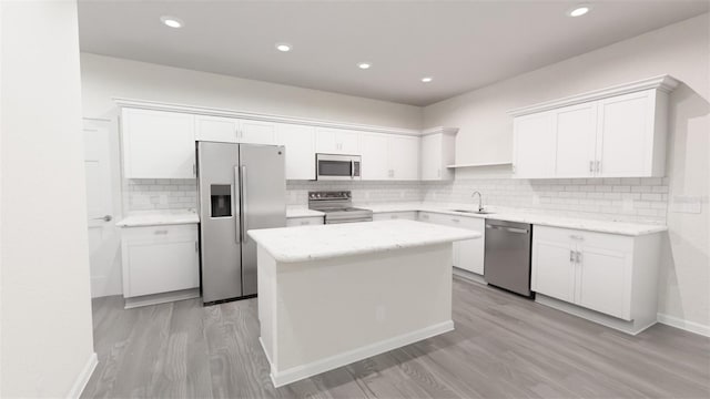 kitchen with a sink, tasteful backsplash, a center island, white cabinetry, and appliances with stainless steel finishes