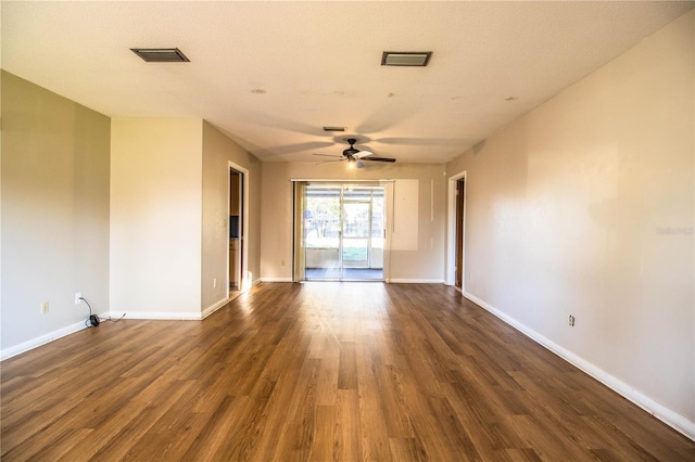 empty room with ceiling fan, dark wood-style floors, visible vents, and baseboards