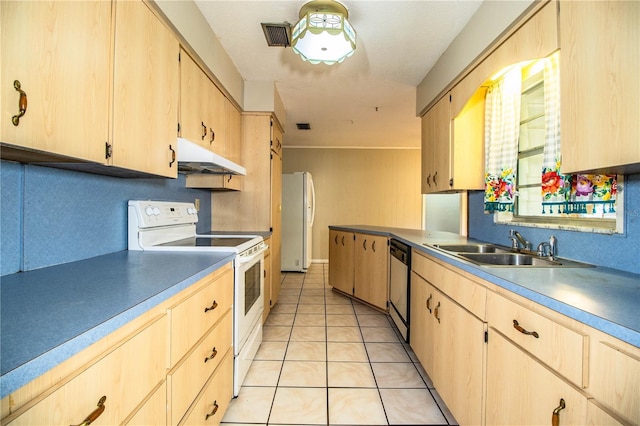 kitchen featuring light brown cabinets, under cabinet range hood, light tile patterned floors, white appliances, and a sink