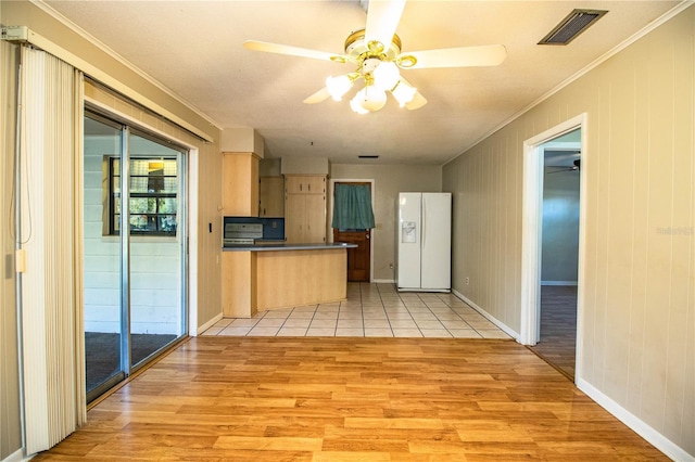 kitchen featuring dark countertops, white refrigerator with ice dispenser, light wood-style floors, and visible vents