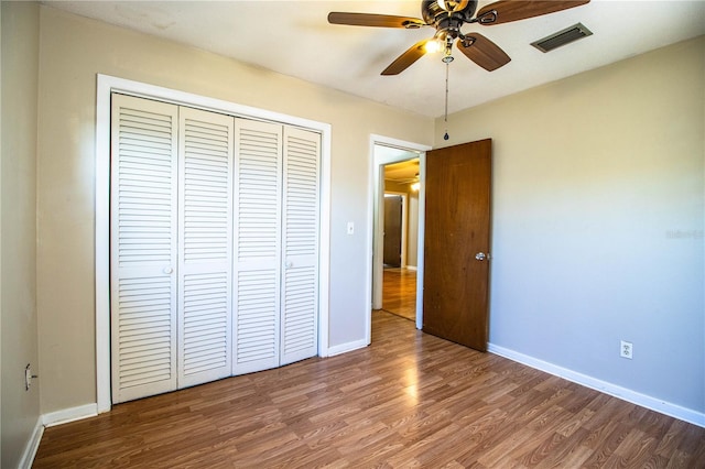 unfurnished bedroom featuring visible vents, wood finished floors, a closet, baseboards, and ceiling fan