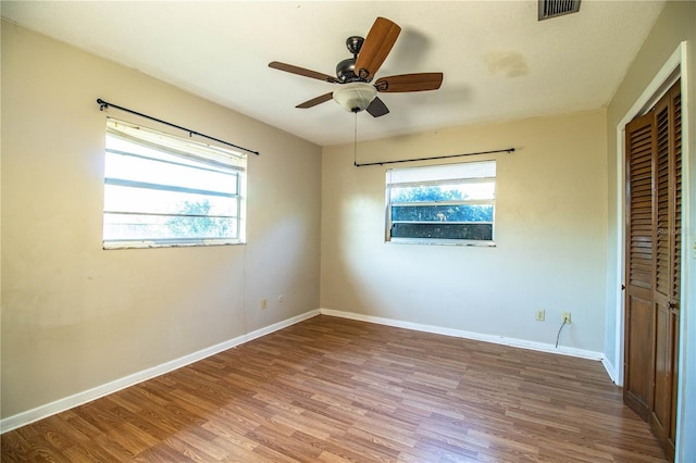 unfurnished bedroom with a ceiling fan, wood finished floors, visible vents, baseboards, and a closet