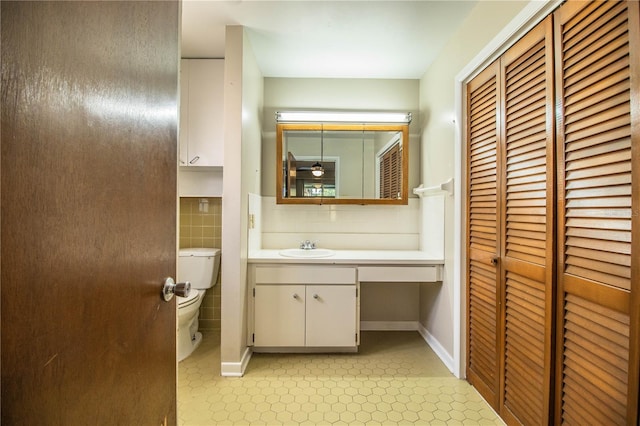 half bathroom featuring a closet, toilet, and vanity