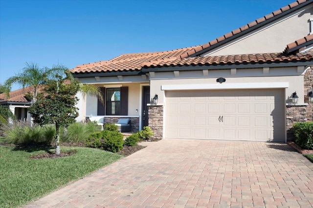 mediterranean / spanish house with stone siding, stucco siding, decorative driveway, and a garage