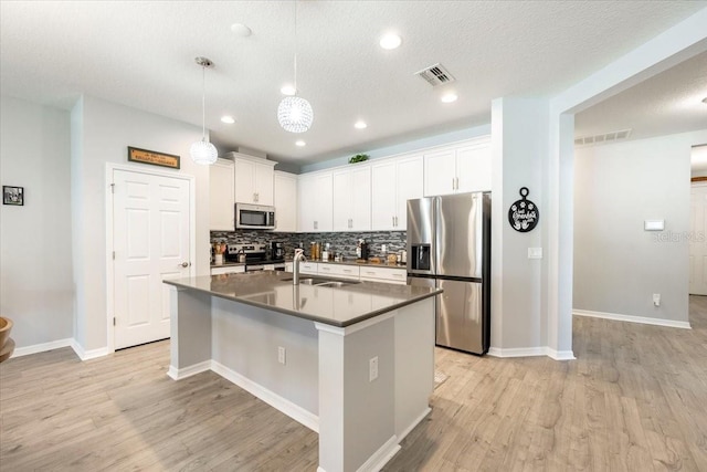 kitchen with visible vents, a sink, backsplash, light wood-style floors, and appliances with stainless steel finishes