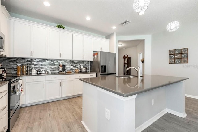 kitchen with dark countertops, light wood-style flooring, stainless steel appliances, and a sink