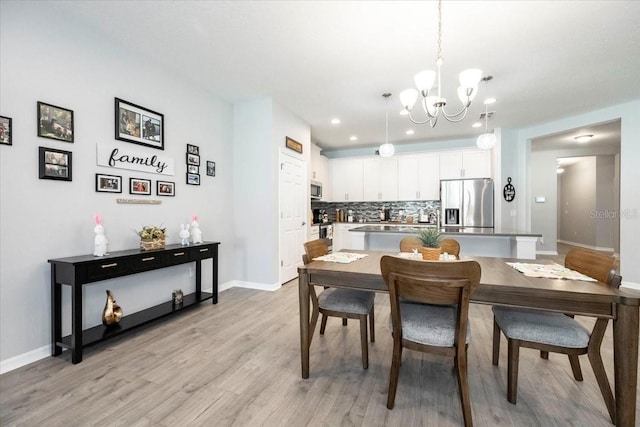 dining area with an inviting chandelier, recessed lighting, light wood-style floors, and baseboards