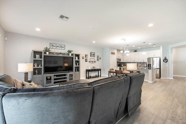 living room featuring baseboards, visible vents, recessed lighting, a notable chandelier, and light wood-type flooring