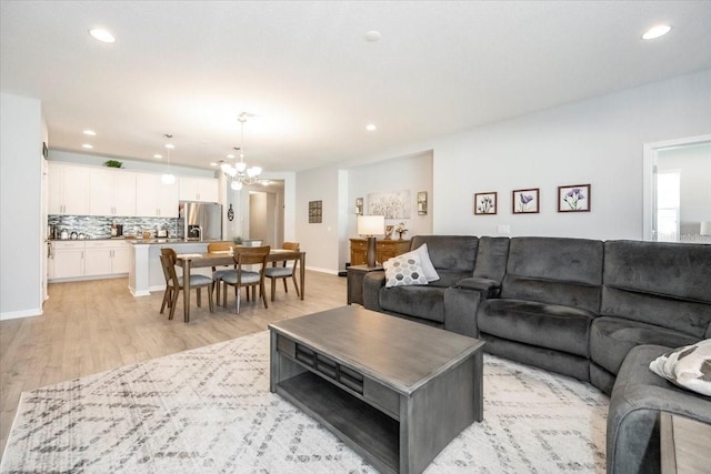 living area with light wood finished floors, recessed lighting, baseboards, and an inviting chandelier