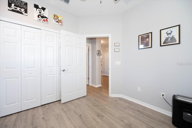 unfurnished bedroom featuring a closet, light wood-type flooring, and baseboards