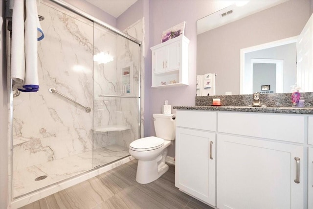 bathroom featuring vanity, toilet, visible vents, and a marble finish shower