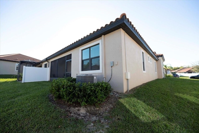 view of home's exterior with a tiled roof, stucco siding, cooling unit, and a yard