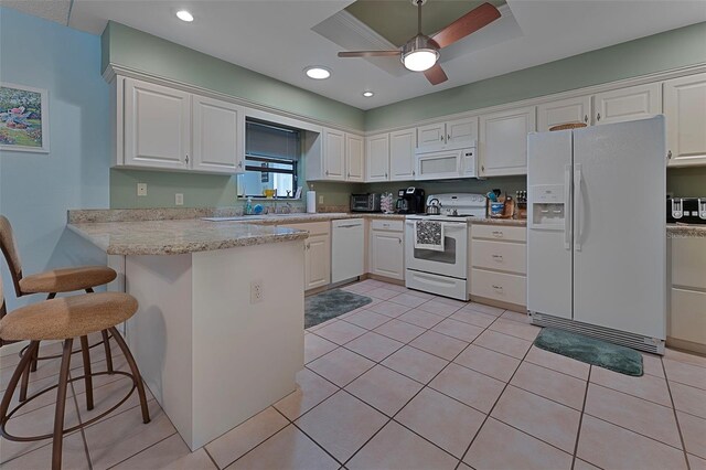 kitchen with white appliances, white cabinets, light tile patterned floors, and a peninsula