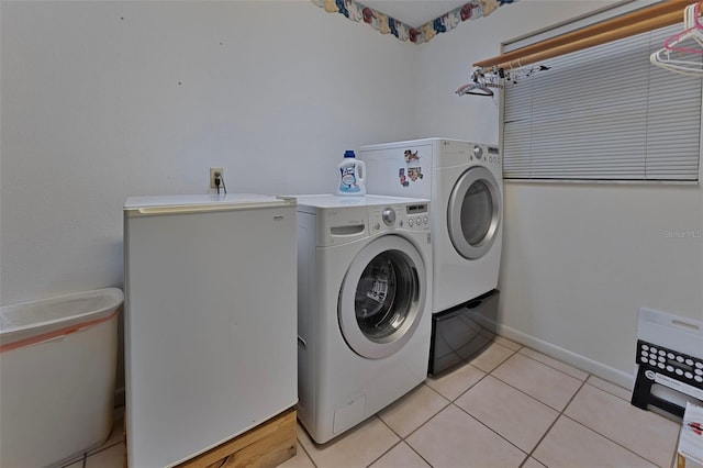 washroom featuring laundry area, light tile patterned floors, washing machine and dryer, and baseboards