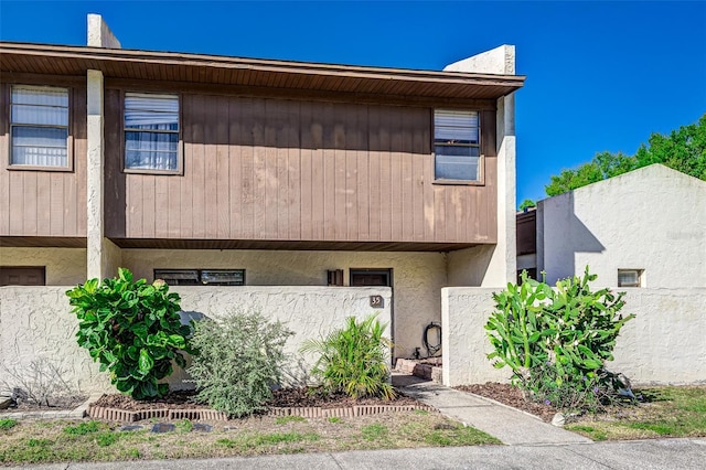 view of property with stucco siding and fence