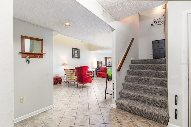 staircase featuring visible vents, baseboards, a textured ceiling, and tile patterned flooring