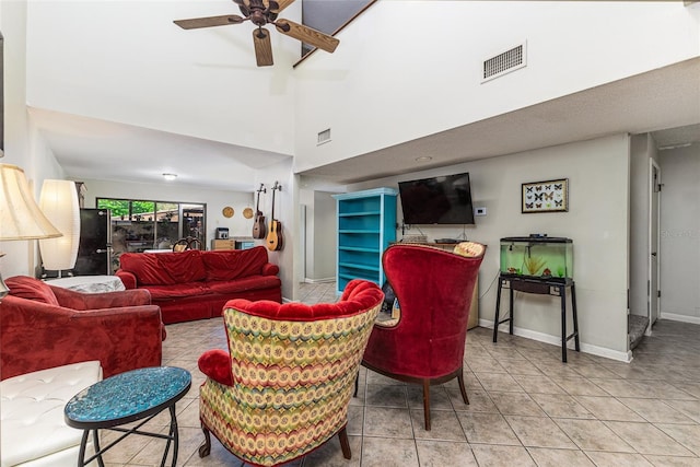 tiled living area with visible vents, baseboards, a high ceiling, and ceiling fan