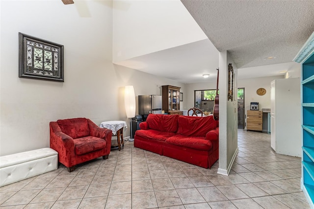 living room with light tile patterned floors, a textured ceiling, baseboards, and a ceiling fan