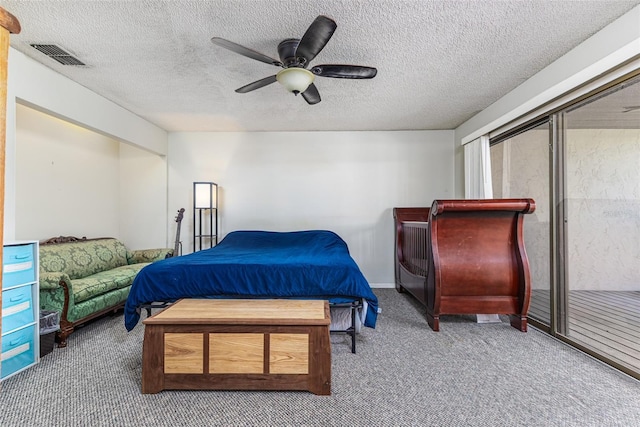 carpeted bedroom with visible vents, a textured ceiling, and ceiling fan