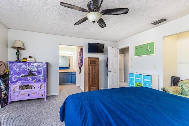 bedroom with visible vents, light colored carpet, connected bathroom, and a textured ceiling