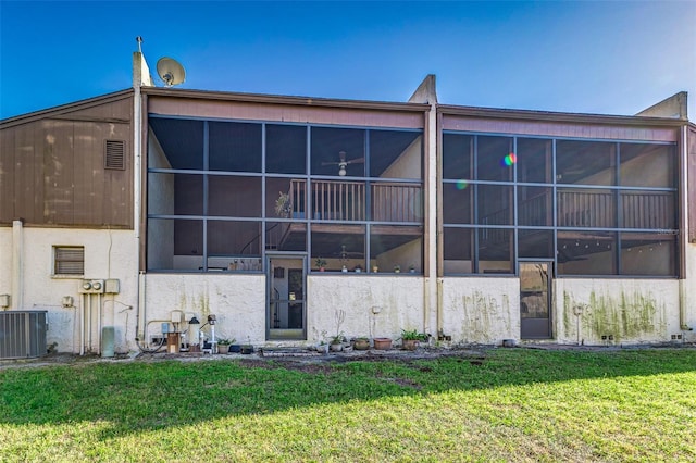 back of house featuring cooling unit, a yard, a sunroom, and stucco siding