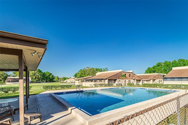 community pool with a patio area, a residential view, and fence