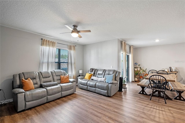 living room featuring ceiling fan, a textured ceiling, and wood finished floors