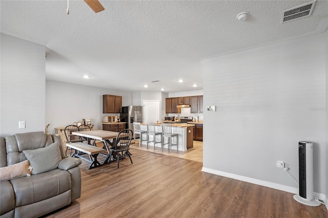 living area with visible vents, baseboards, recessed lighting, light wood-style floors, and a ceiling fan